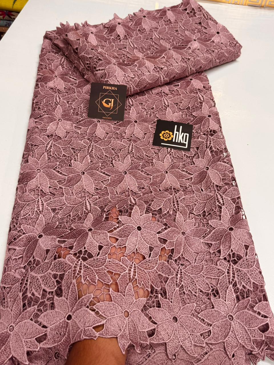Tissu dentelle guipure rose mauve motifs fleurs et feuilles ajournées bord festonné