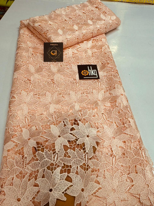 Tissu dentelle guipure rose pêche motifs fleurs et feuilles ajournées bord festonné